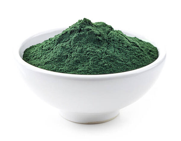 Bowl of spirulina algae powder isolated on white